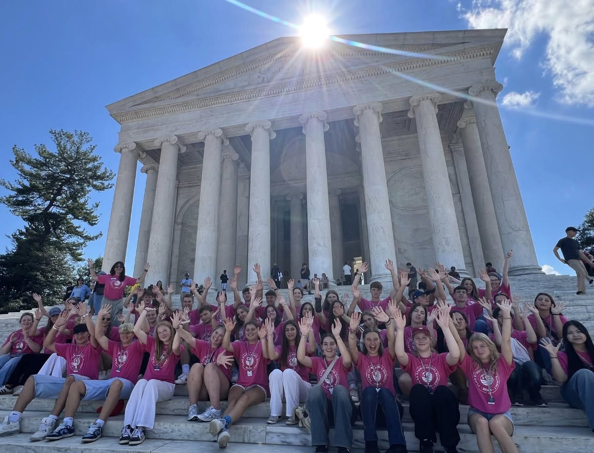 Skupina studentů v růžových tričkách FLAG Leadership Summit na schodech památníku Thomase Jeffersona ve Washingtonu, D.C.