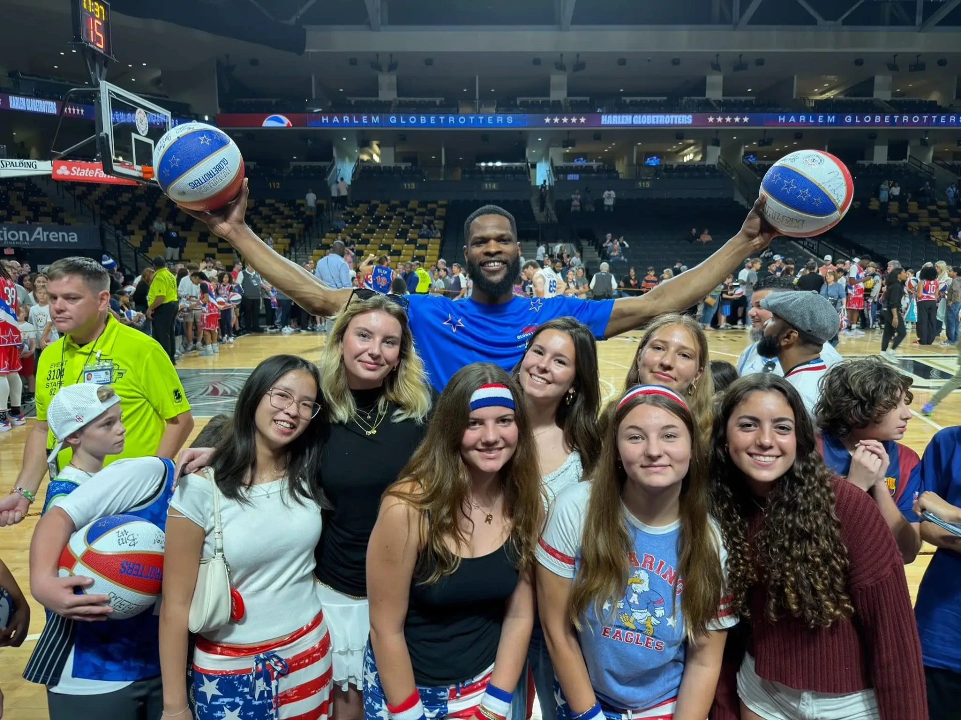 Hráč Harlem Globetrotters s basketbalovými míči obklopený fanoušky na basketbalové aréně v USA